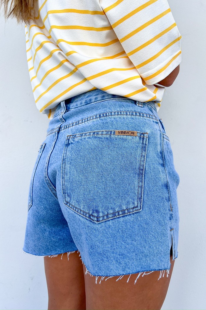 Close-up da lateral do Shorts Domênica, destacando a pequena abertura na perna e a textura do jeans 100% algodão.