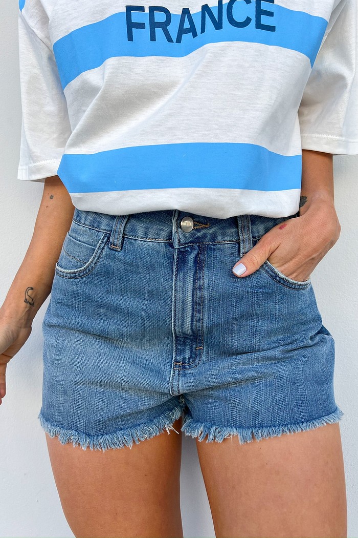 Look casual feminino composto por shorts jeans azul Denim Cleo com barra desfiada e blusa branca básica, ideal para dia a dia e passeios.