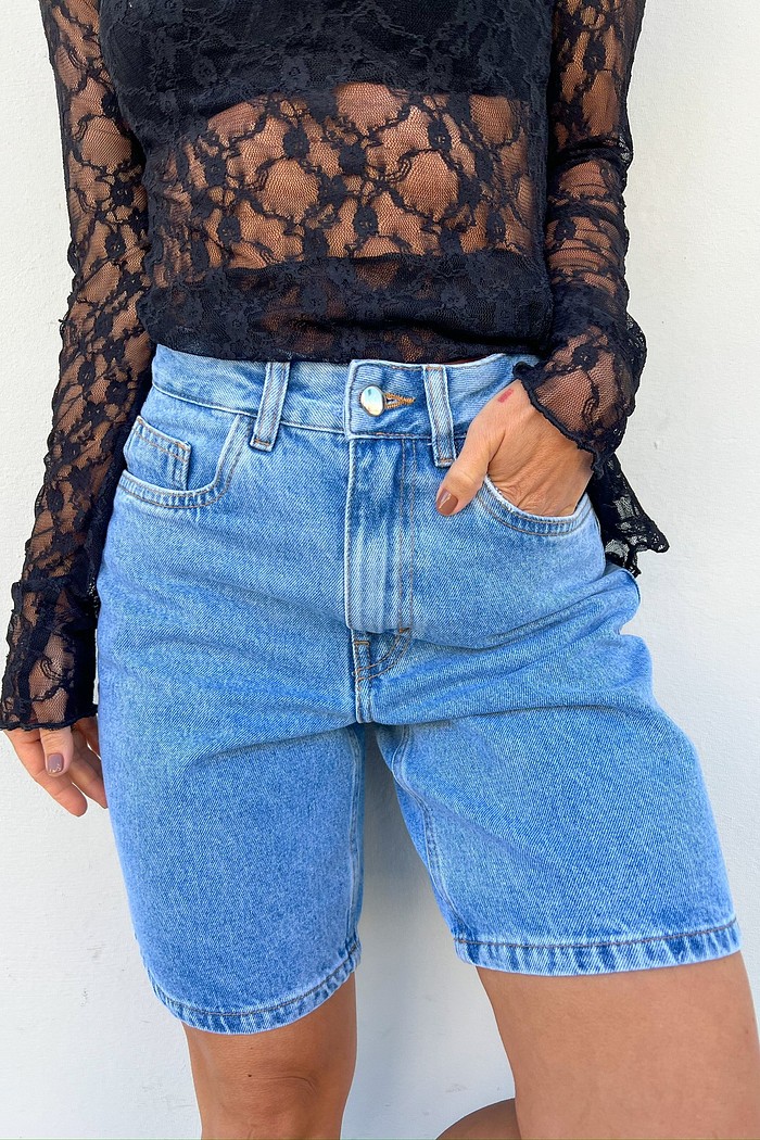 Modelo vestindo a Bermuda Jeans Mom Lia na cor light blue, mostrando a cintura alta e o comprimento mais alongado da peça.