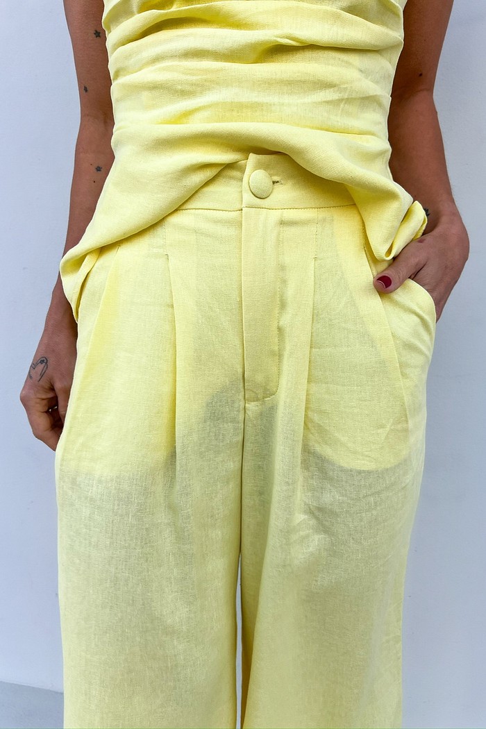 Close-up da região do cós e do bolso faca da Calça de Linho Amarela Eveline, destacando o acabamento de alfaiataria.
