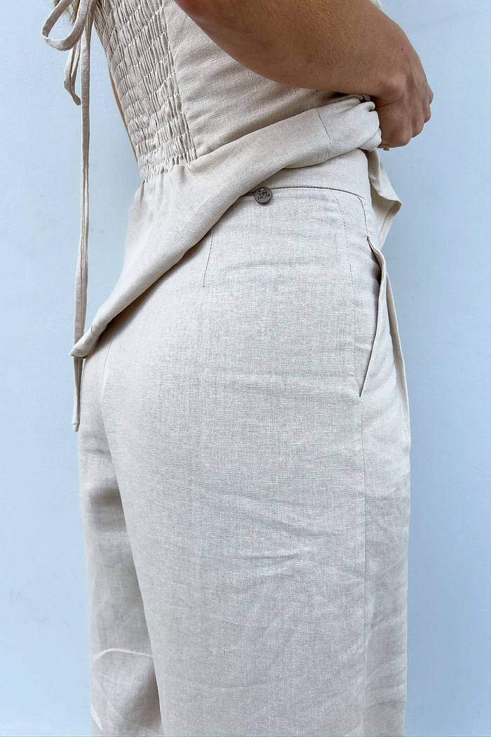 Close-up da região do cós e do bolso faca da Calça de Linho Areia Eveline, destacando o acabamento de alfaiataria.