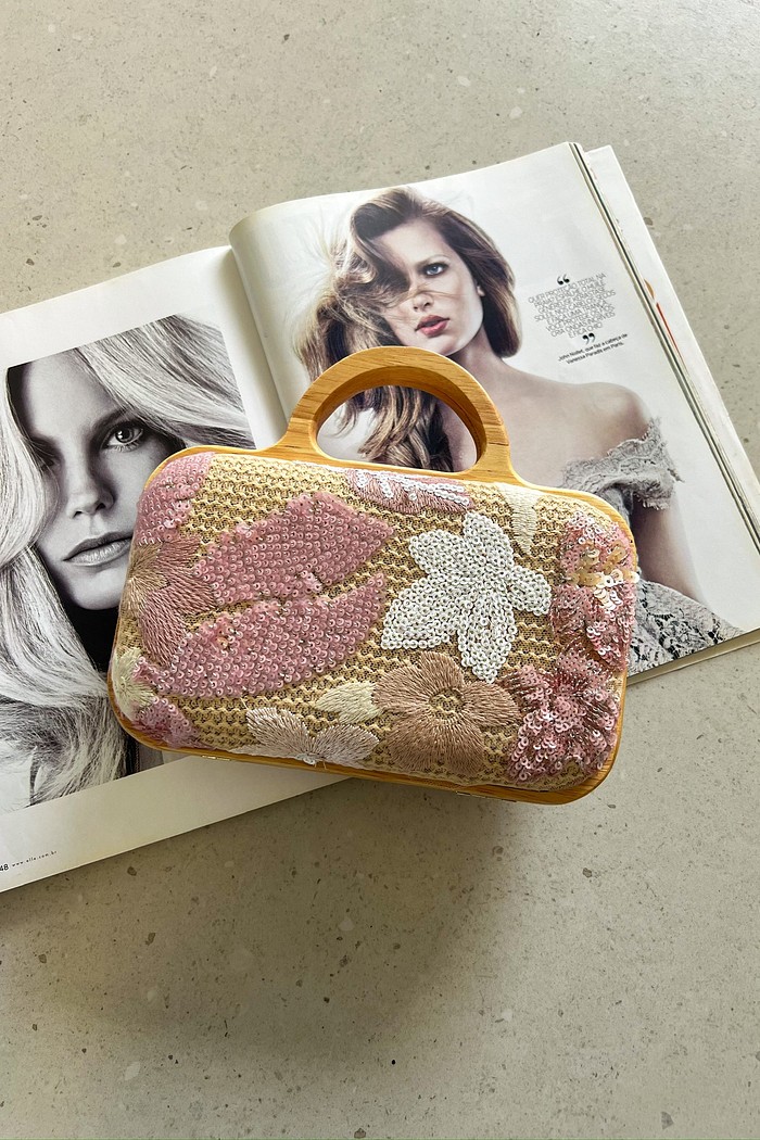 Clutch Flora Rosê com as duas opções de alça: a de mão em madeira e a alça longa de corrente dourada ao lado, mostrando sua versatilidade.